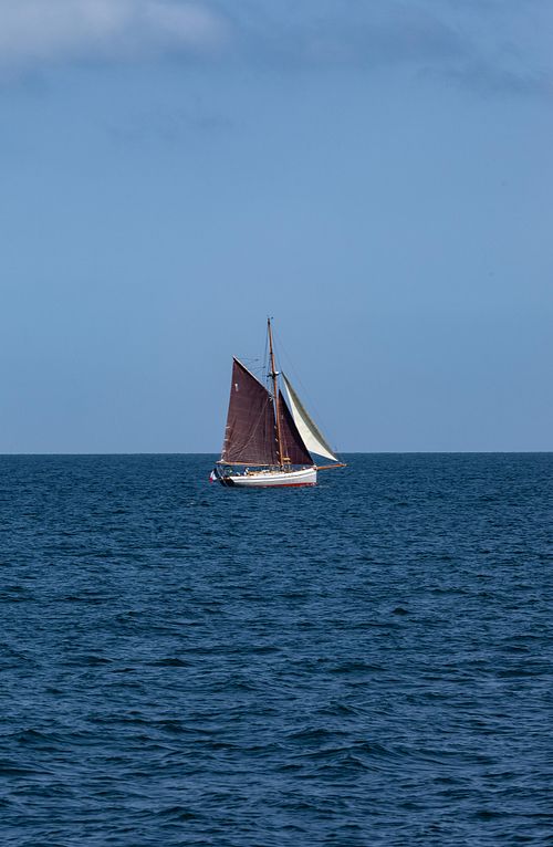 Voilier sur mer bleue et horizon dégagé.