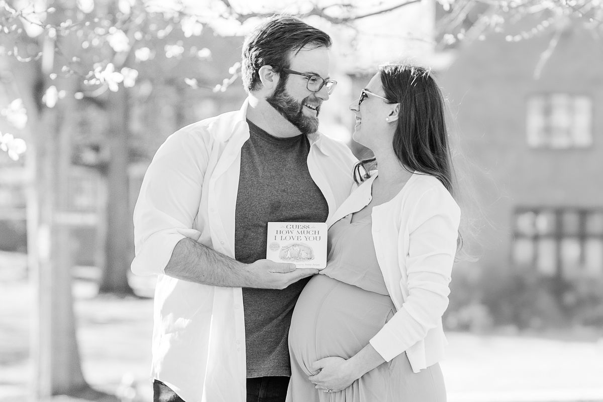 B&W of husband and expectant wife smiling and holding Guess How Much I Love You book at The Frick