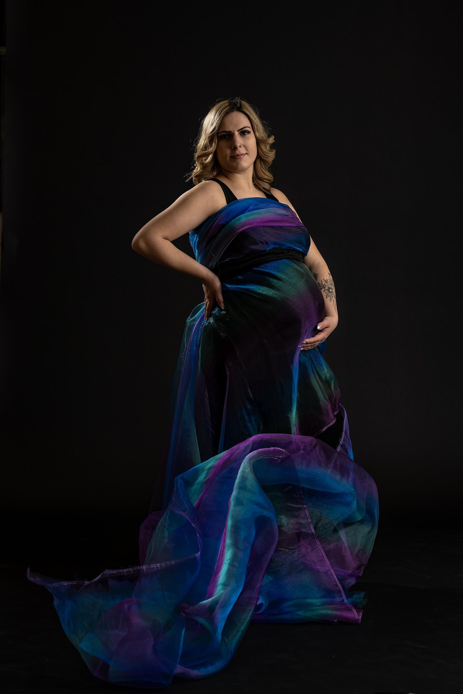 Creative portrait of expecting mother with rainbow fabric flowing around her.