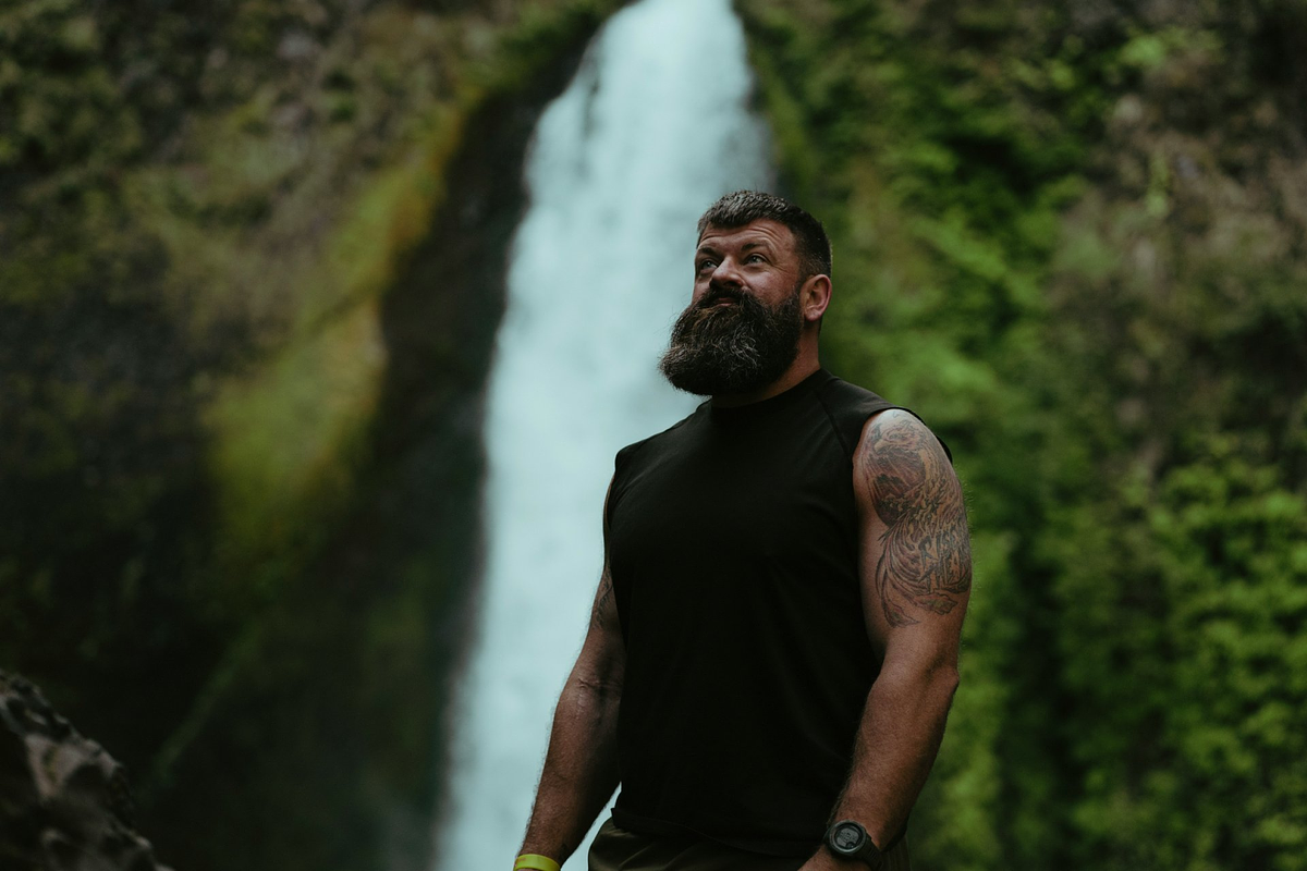 Image of a male model posing beside a waterfall