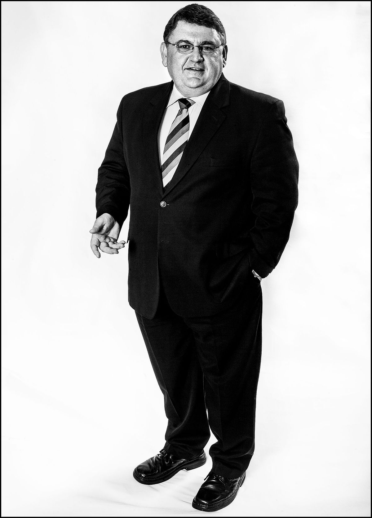 Portrait of a business man dressed in a dark suit standing on a white seamless background