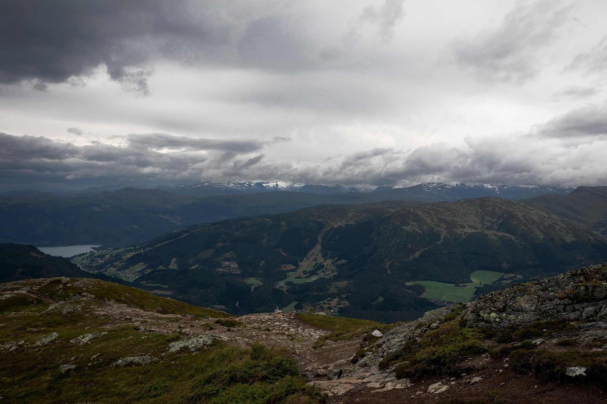 Vallée rocheuse avec cours d’eau, ciel nuageux.