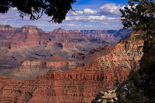 A wide-angle fine art photograph of the Grand Canyon from the South Rim, showcasing the layered red rock buttes and deep shadows under a dramatic Arizona sky