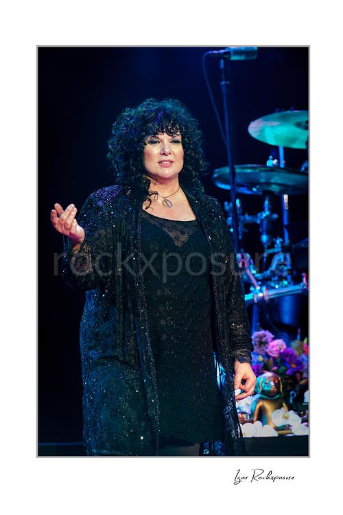 Vertical color image of Ann Wilson performing live on stage during a Heart concert in a close portrait with blue stage light