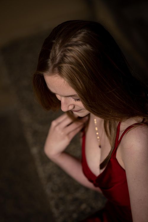 Portrait of graduating young woman from above in her red dress.