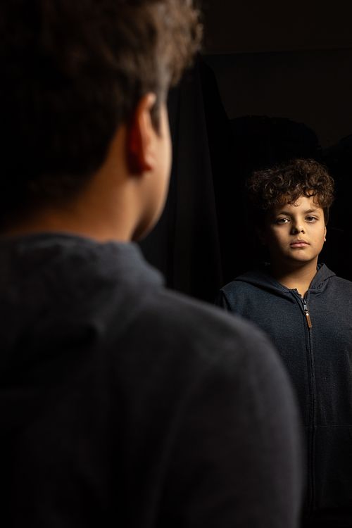 Young boy looking into mirror with serious expression, conceptual portrait photography in Stockholm