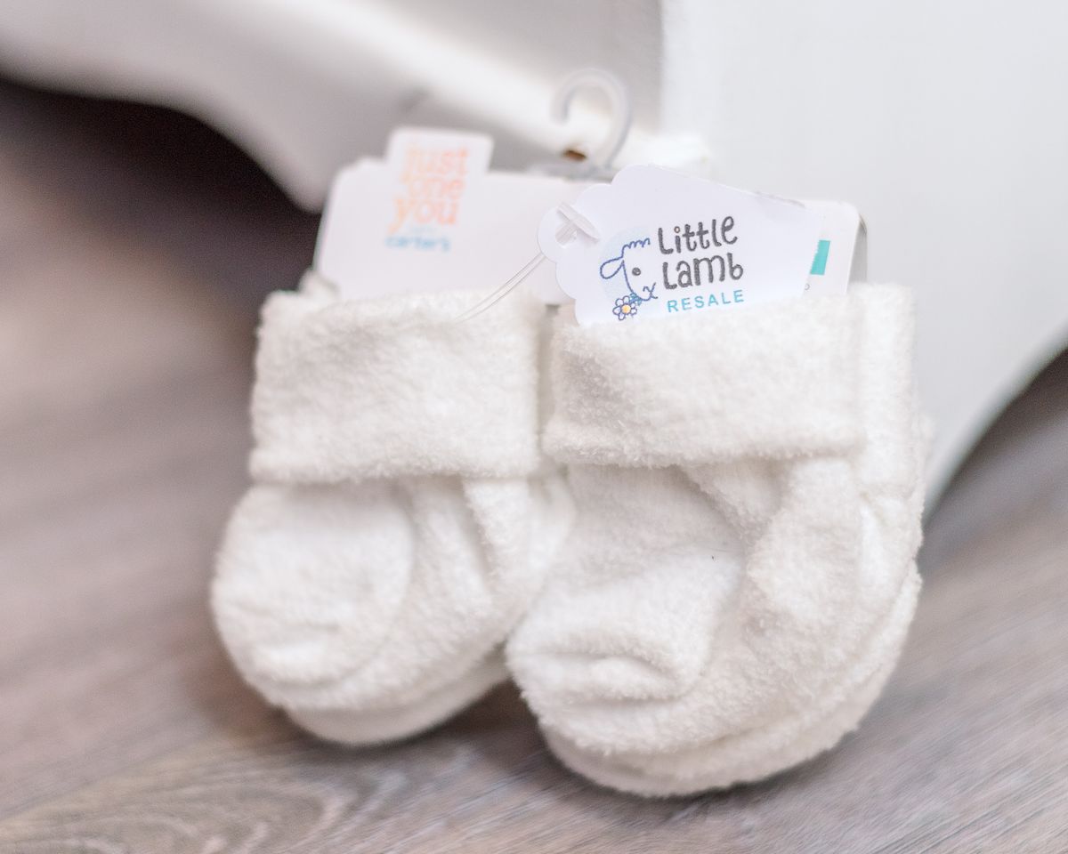 Newborn baby socks in white posed against a white dresser corner