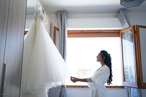 "la sposa guarda l'abito prima di indossarlo"