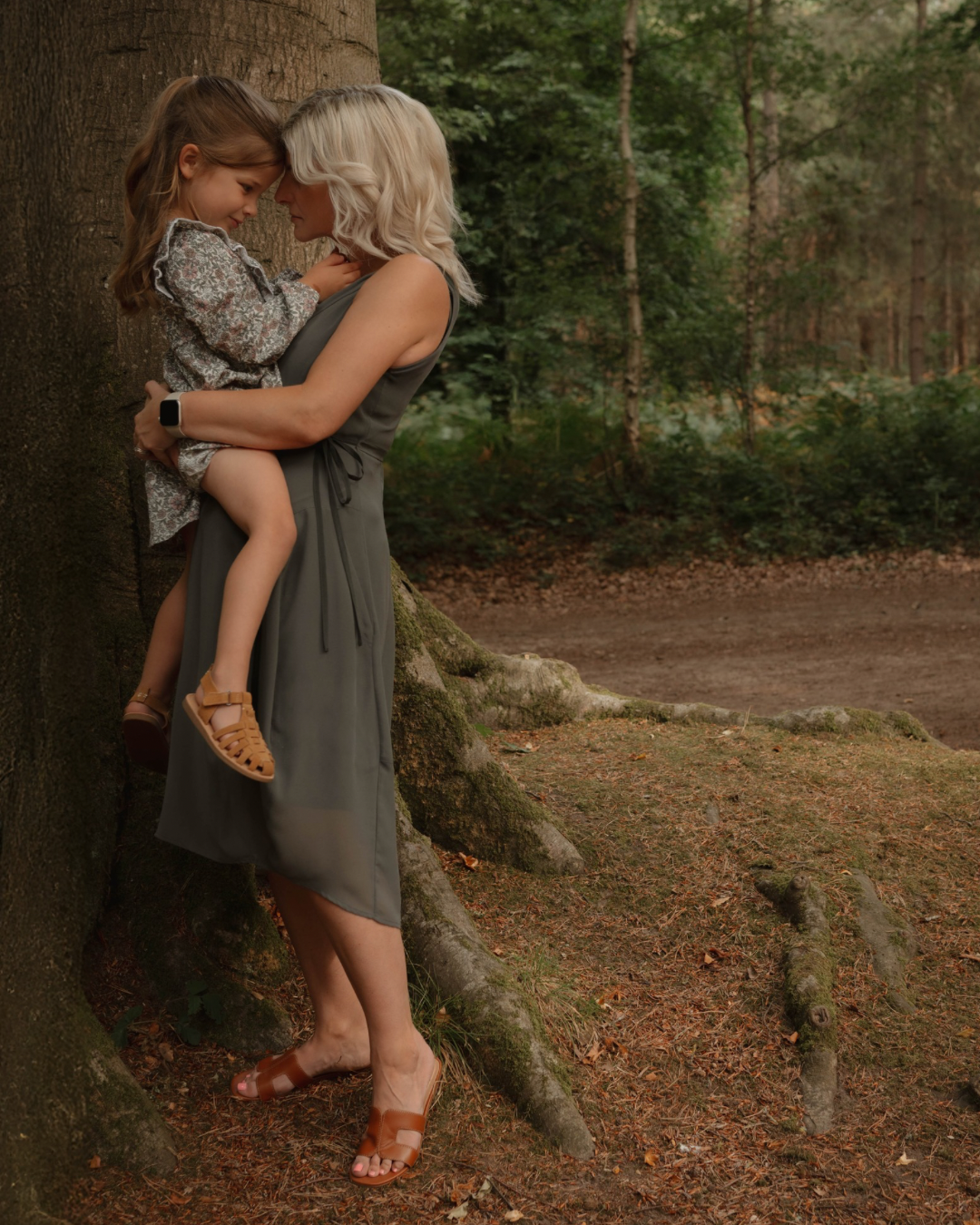 Mother cradling toddler in dappled woodland light, family lifestyle photography Northamptonshire