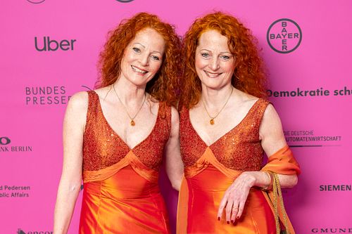 Hannover sisters in matching red gowns posing on the pink carpet at Bundespresseball 2024.
