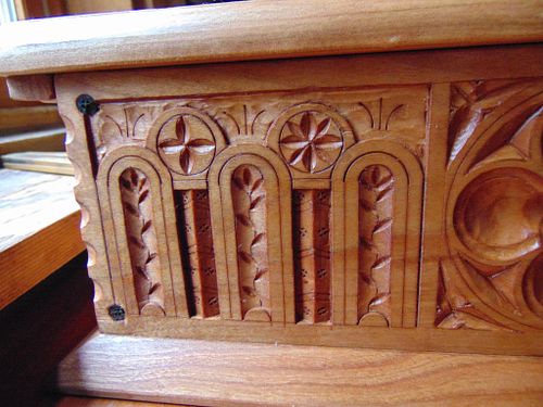 a detail of the face carving on the cherry ordination box