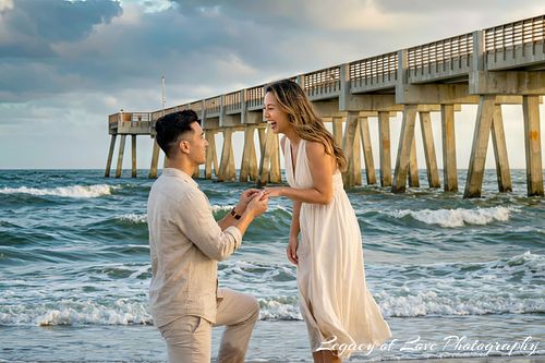 Man proposing to woman on the beach near Jacksonville Beach Pier, captured by Legacy of Love Photography.