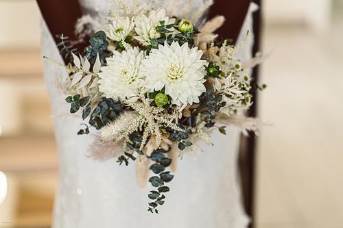"mani di sposa che tengono bouquet di fiori chiari"