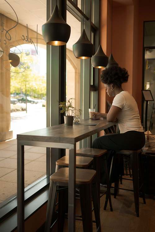 A person working at a table in a café near a large window with natural light