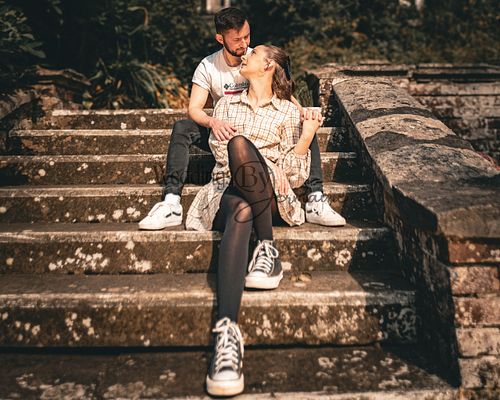 Alex and Shelby sitting together on the outside steps in the botanical gardens in Oadby, captured by Weddings by Jermaine during their engagement shoot, showcasing their love and connection