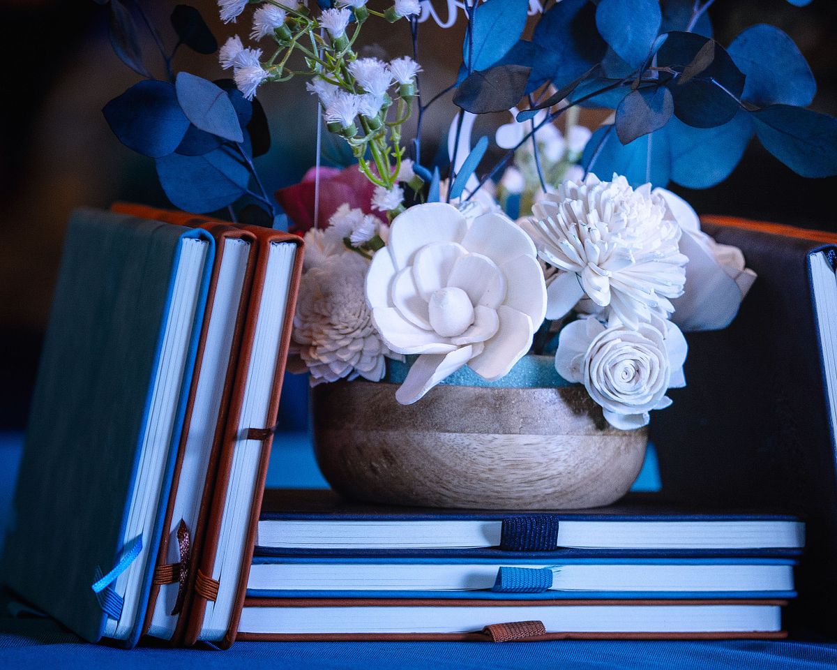 detail shot of flower arrangements and journals stacked next to the flower arrangement.