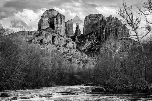 A powerful black and white fine art landscape of Castle Rock in Sedona, Arizona, during sunset, highlighting the long shadows and dramatic textures of the sandstone spires