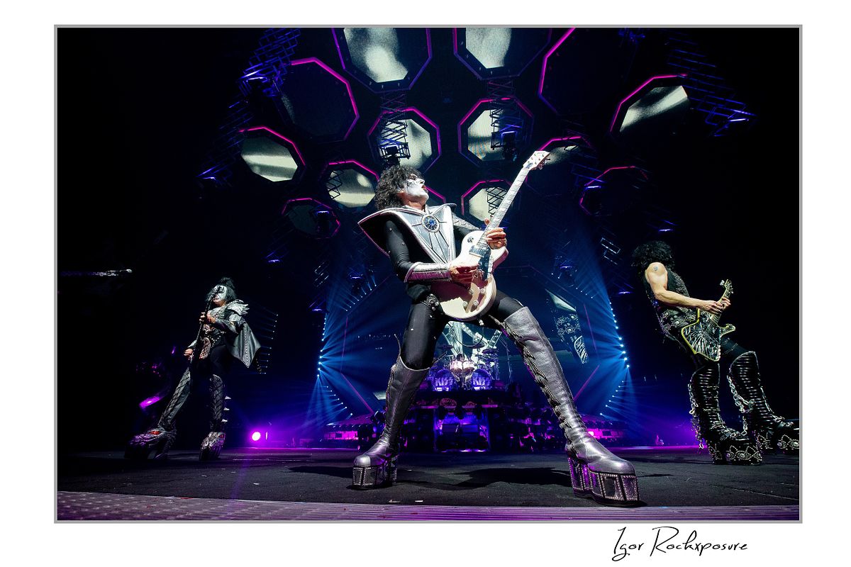 Tommy Thayer in full makeup playing white guitar, with Paul Stanley and Gene Simmons visible
