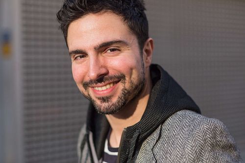 Toni Gojanovic in a gray jacket and striped hoodie smiling.