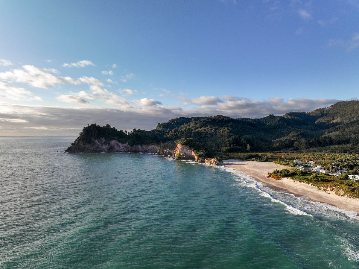 Cinematic aerial drone photography of Whiritoa Beach and coastal residences by Flax Cove Studio.