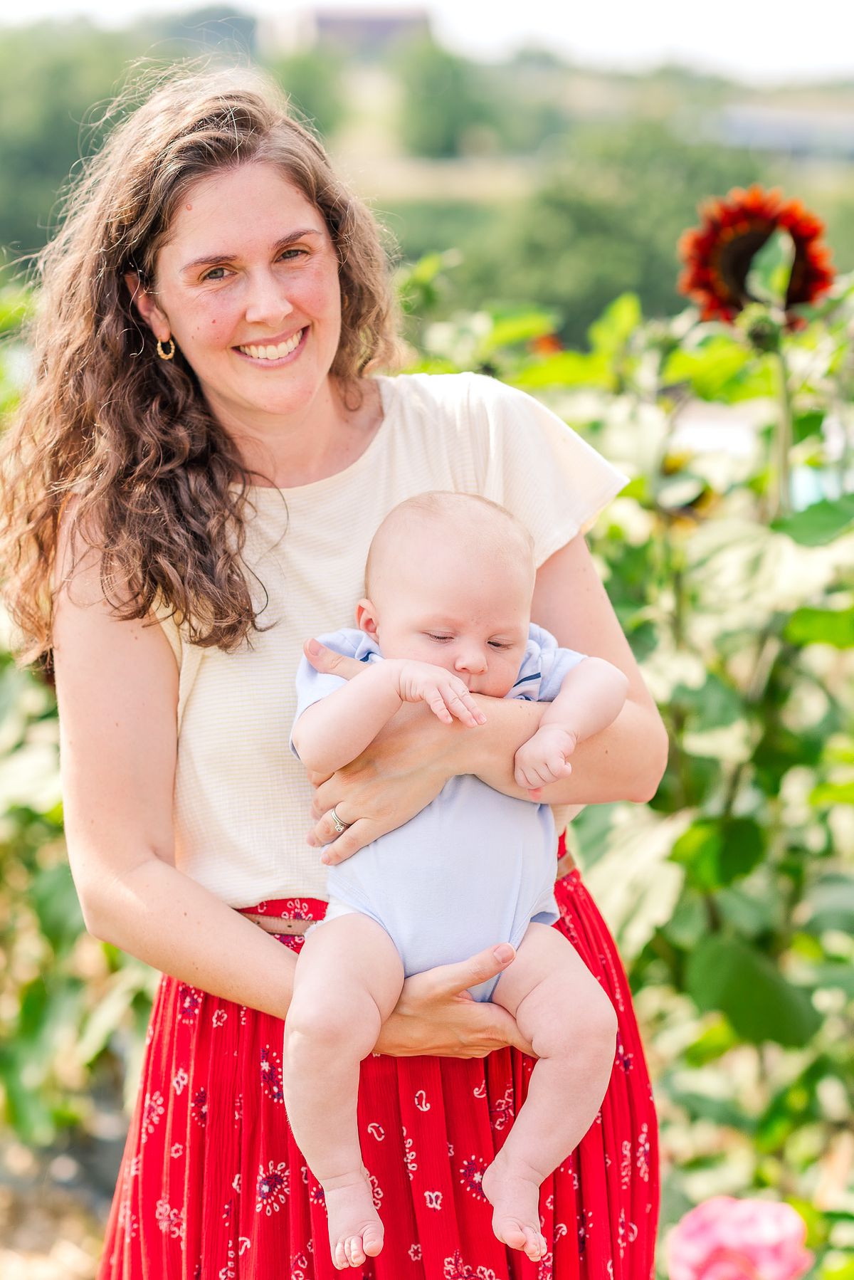 mom holding baby in sunflower garden with cranberry township, pa newborn photographer
