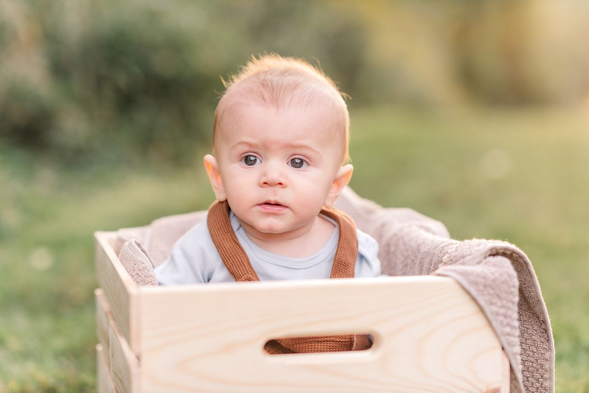 Baby sitting in a crate looking serious