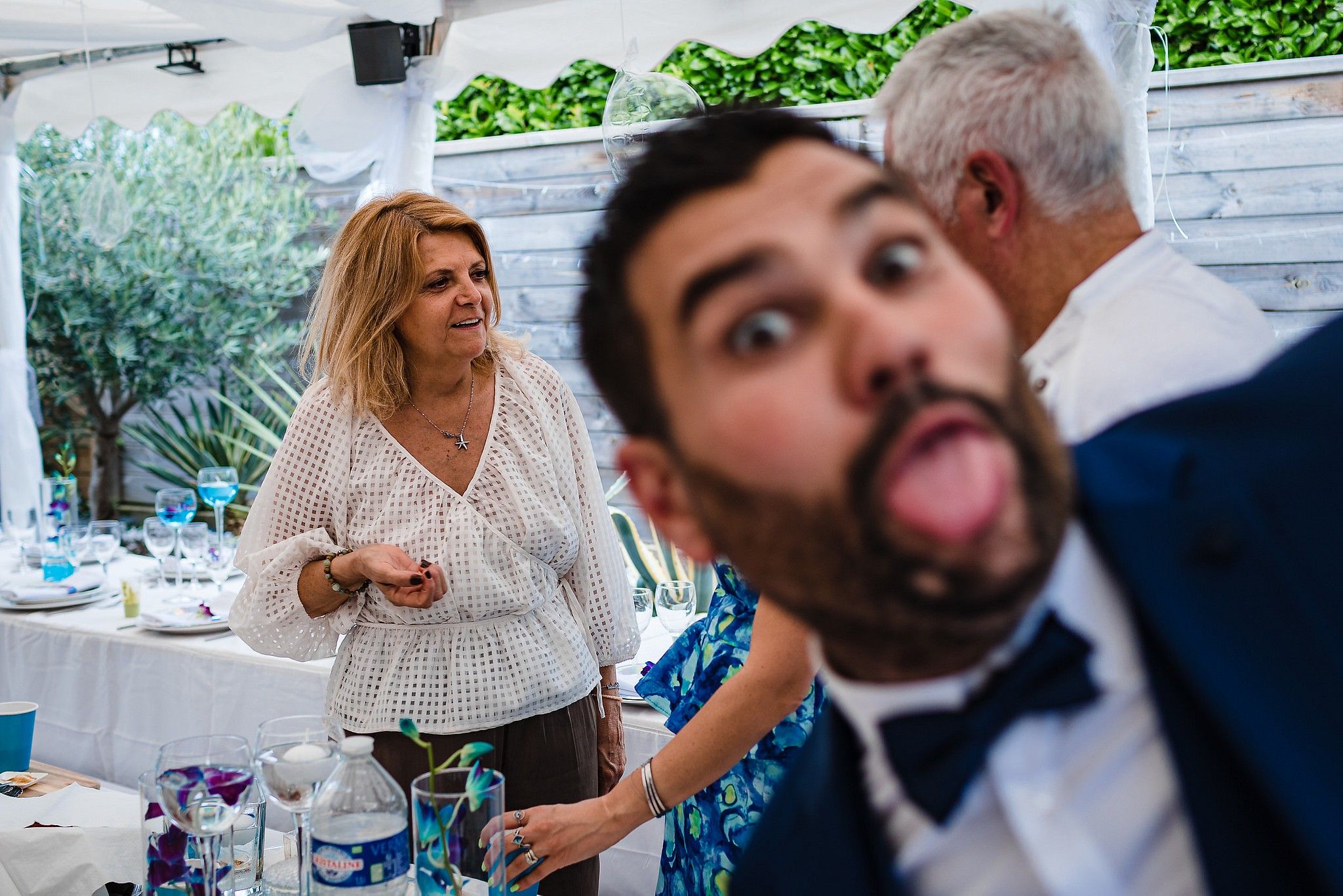 Mari&eacute; qui fait une grimace pendant que le photographe prend une photo de sa belle-maman captur&eacute; par S&eacute;bastien CLAVEL photographe de Mariage &agrave; Lyon et Gen&egrave;ve
