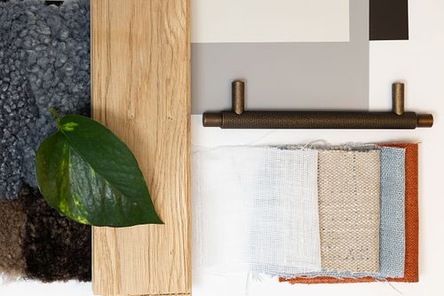 Flatlay med tygprover, träprov, blad och beslag som moodboard för inredningsdesign och materialval.