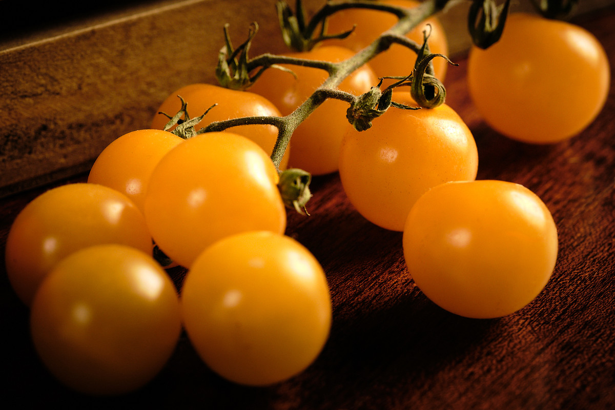 Macro image of yellow cocktail tomatoes on mahogany wood.