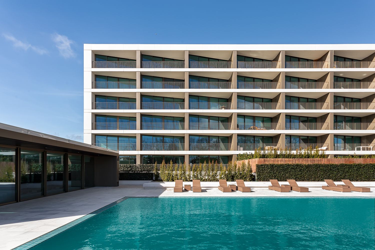 Fachada moderna do edif&iacute;cio Legacy Residences em Cascais, com piscina e &aacute;reas exteriores, fotografada por Pedro Br&aacute;s Photography &mdash; fotografia profissional de arquitetura e imobili&aacute;rio de luxo em Portugal.