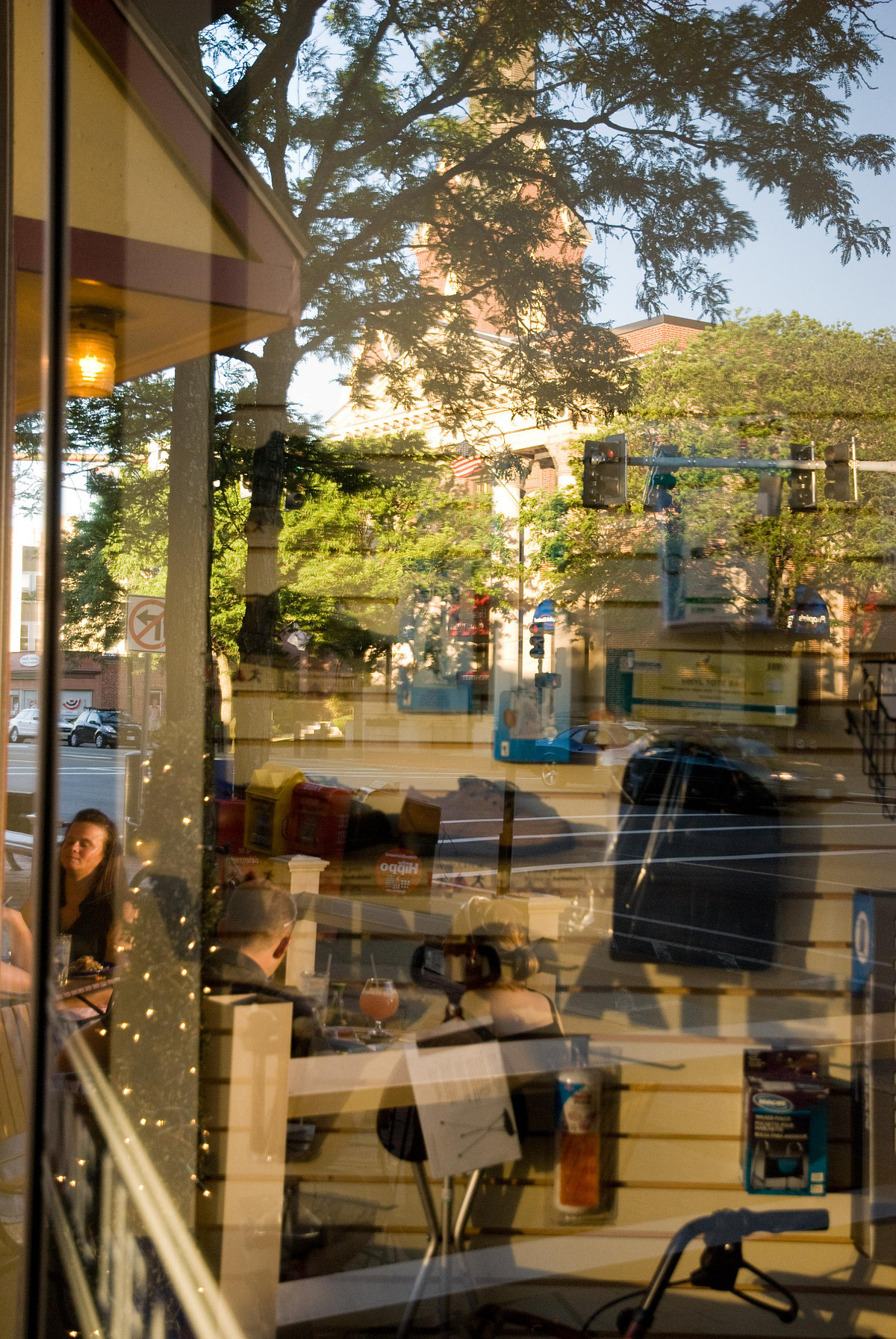Pharmacy window with medical supplies seen inside and patrons dining on street outside