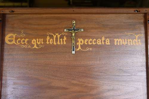 the reredos with the crucifix and the text from the Mass: Ecce qui tollit peccata mundi