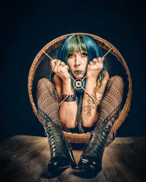 Portrait artistique d&rsquo;une femme aux cheveux color&eacute;s accroupie dans un abat-jour, symbolisant l&rsquo;enfermement psychologique, la prison mentale et la lutte pour se lib&eacute;rer &mdash; &oelig;uvre de Pascal Yennis, Namur, Belgique.
