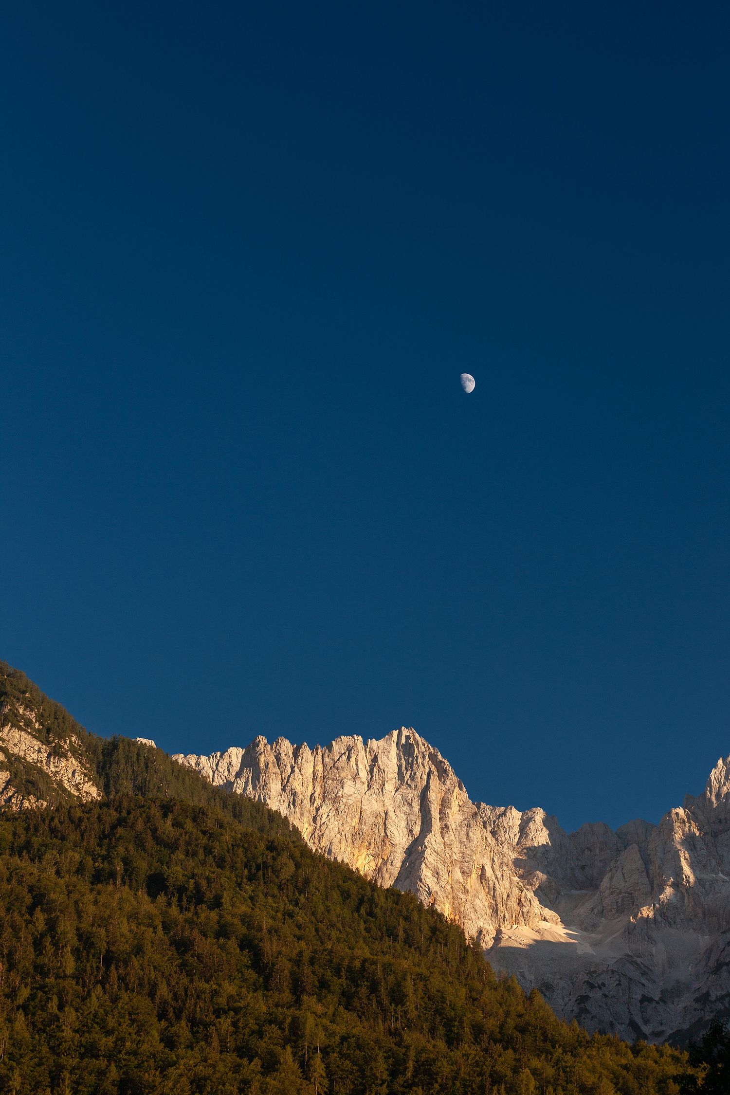 Sunset over the Slovenian mountains, with the moon in the sky