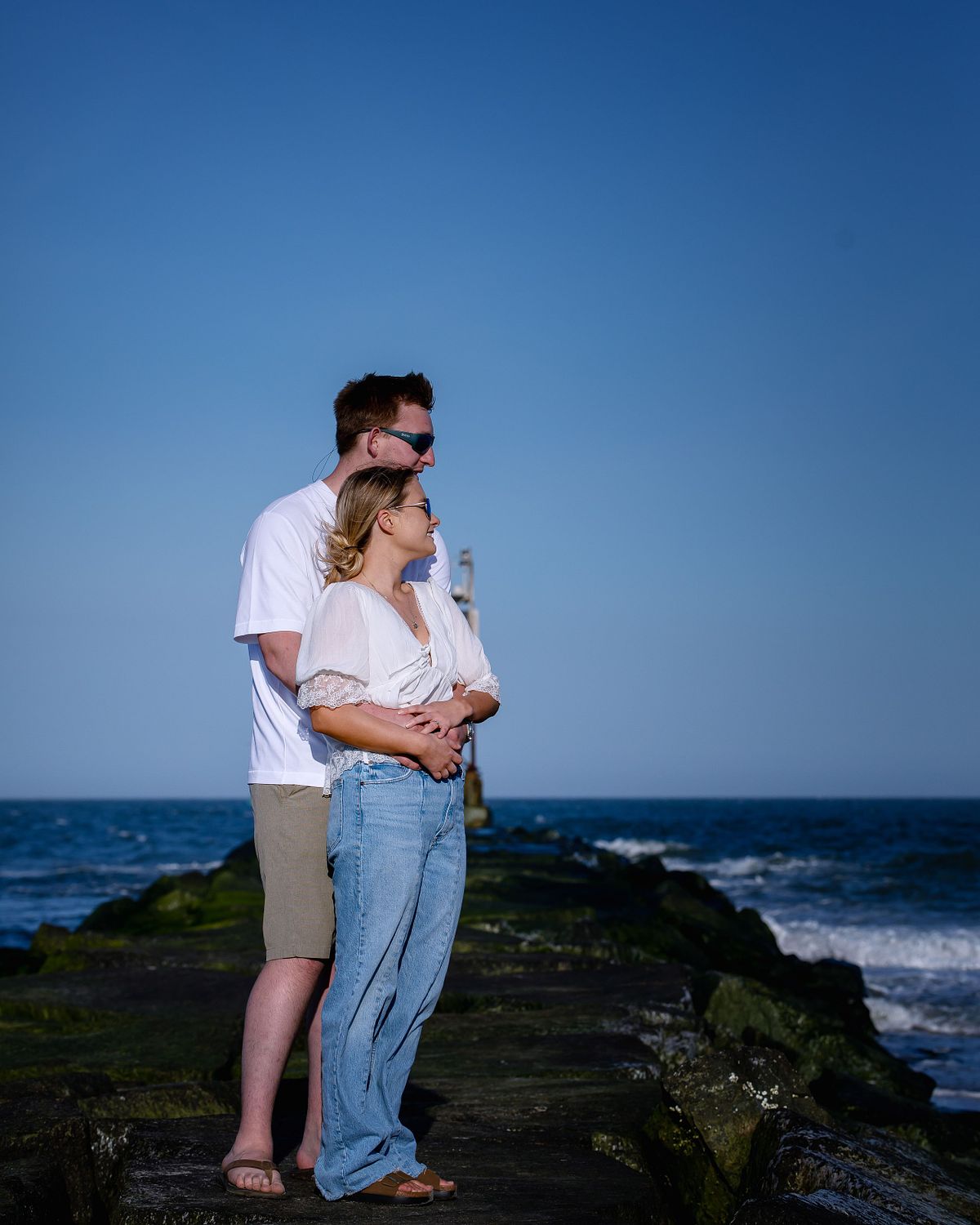 couple standing on the jetty at indian river inlet, in sussex county, during engagement session