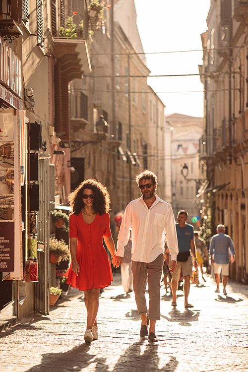 "coppia passeggia tenendosi per mano fra le strade di Alghero"