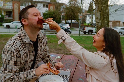 couple sharing pizza in a park