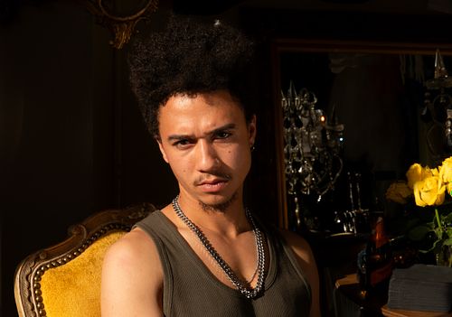 Black man sitting in vintage chair moodily posing