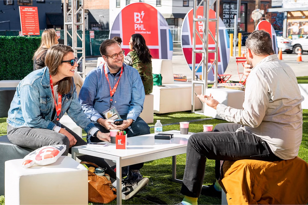 Corporate event photography capturing attendees networking and sharing ideas during an outdoor session at the B.PHL Innovation Festival 2023 in Philadelphia, highlighting collaboration, creativity, and community in a relaxed setting.
