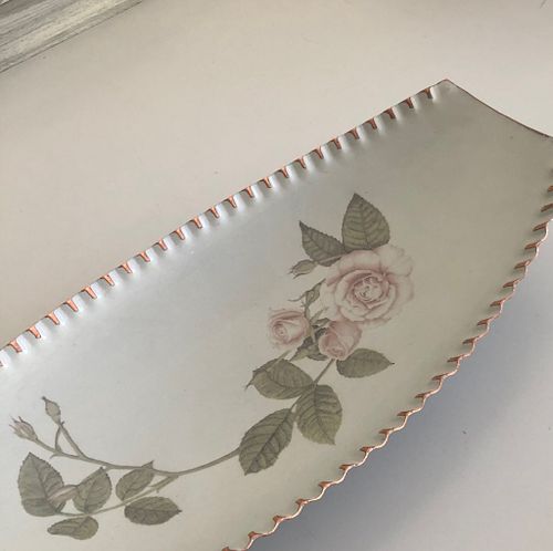 Vintage serving plate with delicate rose design and scalloped edges, featuring soft pink and green tones.