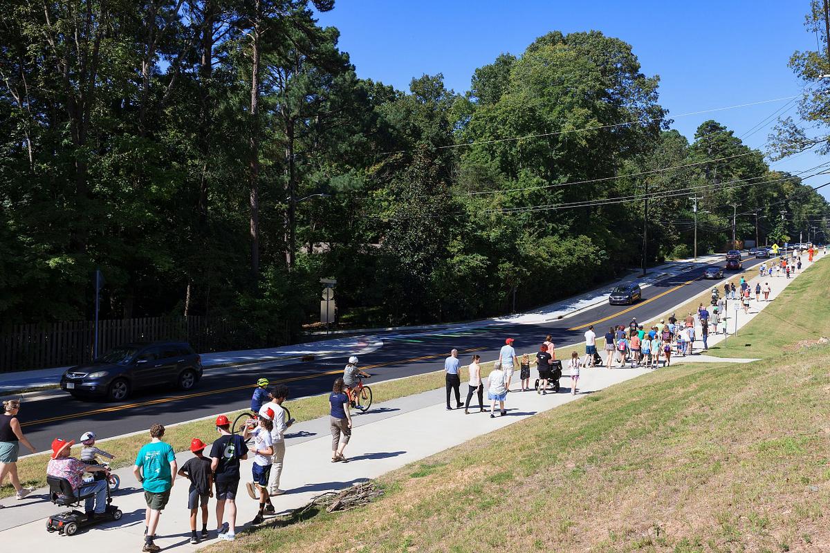 People walking on Estes Road at the sidewalk opening in Chapel Hill, NC