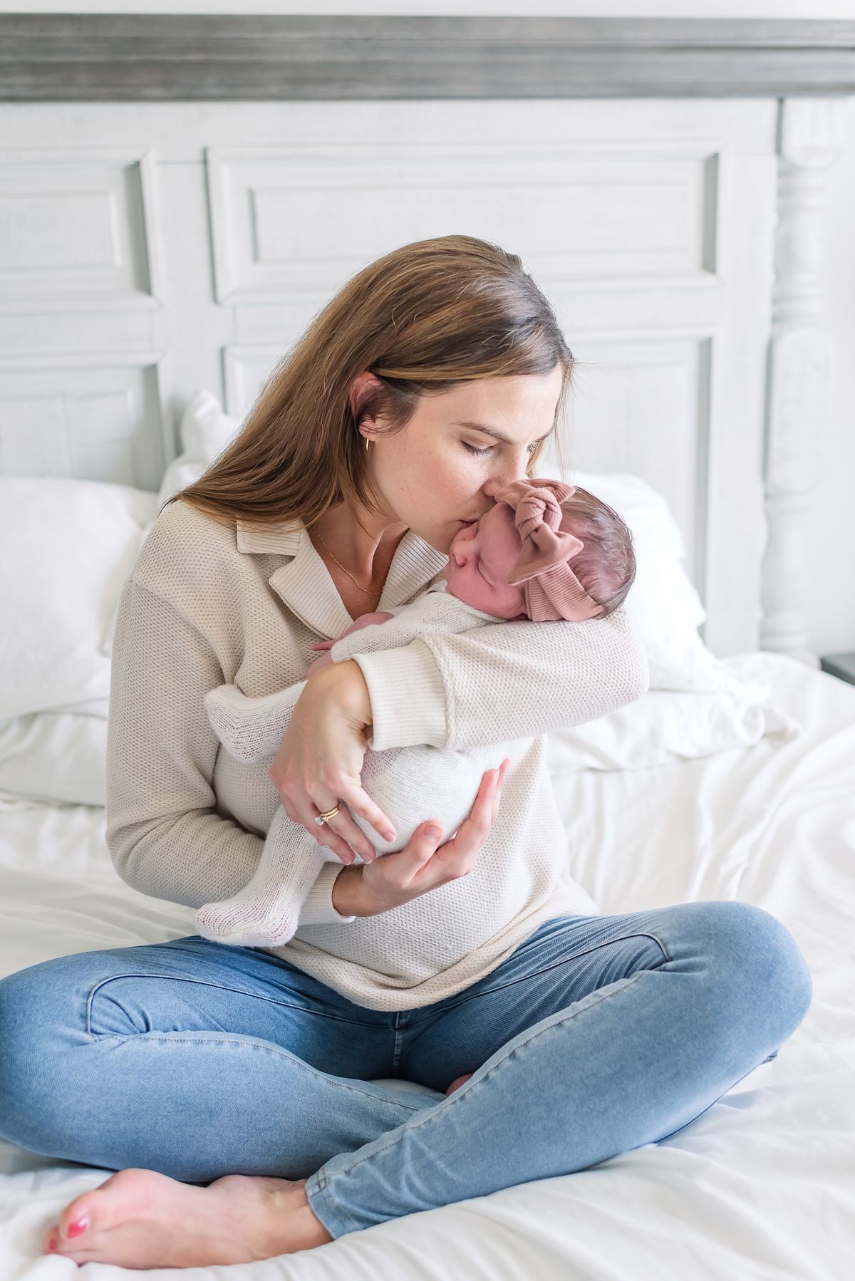 mom in neutral colored clothes and room kissing her newborn baby's cheek with cranberry township, pa newborn photographer