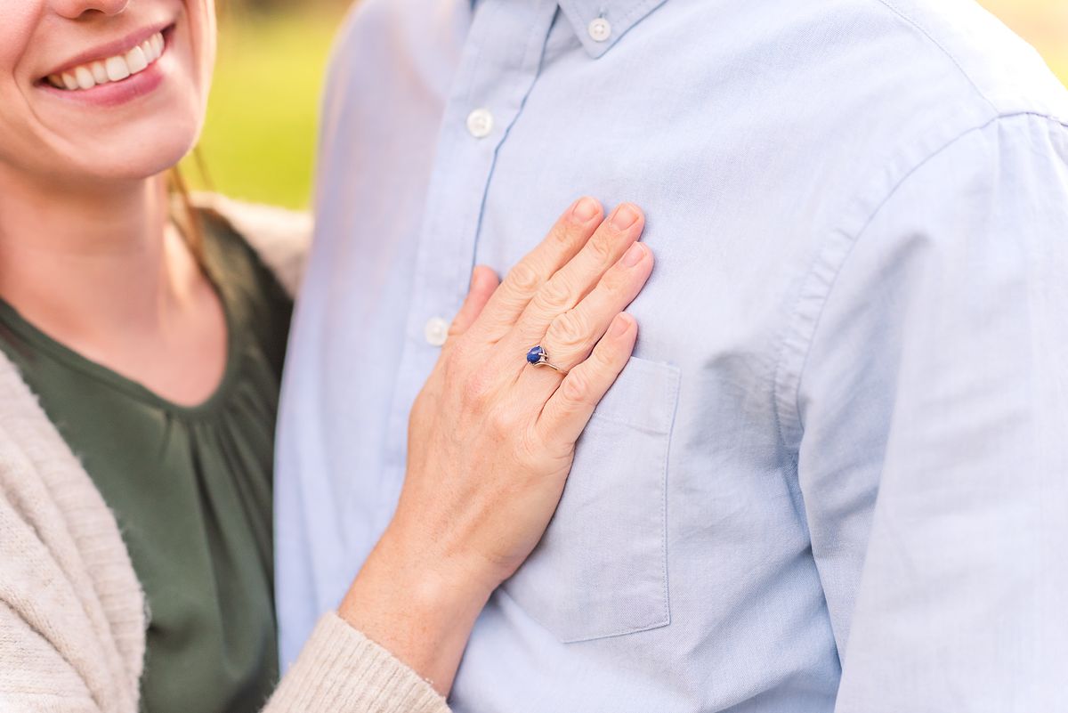 wife smiling with hand on husband's chest showing a blue stoned ring with Cranberry Township, PA newborn photographer