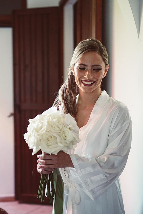 "sposa riene bouquet in mando in vestaglia prima di indossare abito matrimonio"