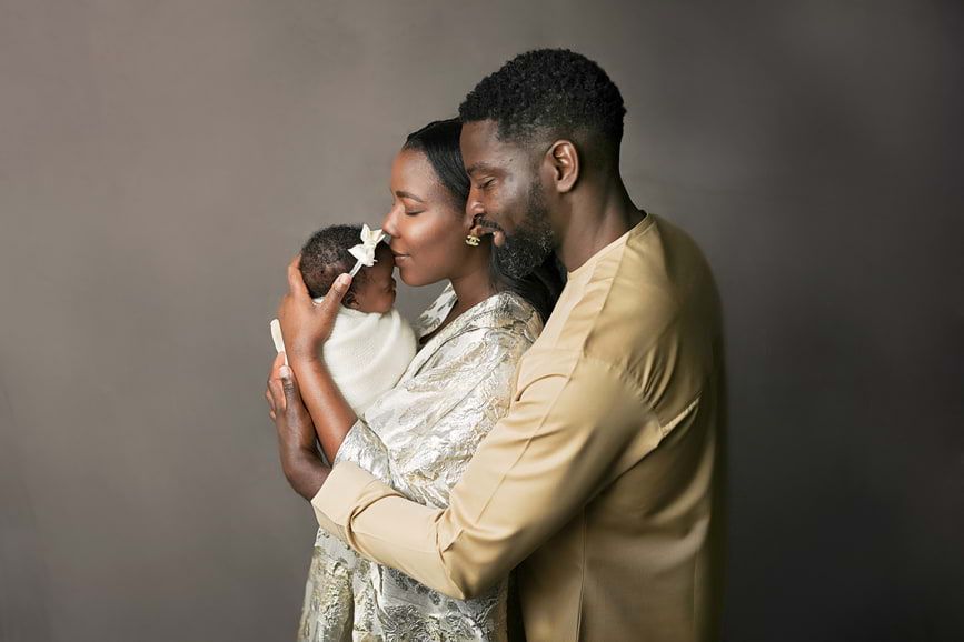 Heartwarming family portrait featuring parents holding their newborn, captured by Houston newborn photographer Amanda Mandola.