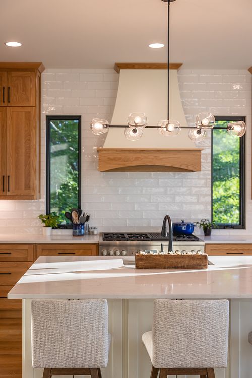 Narrow windows framing the range and hood centered with island and sink