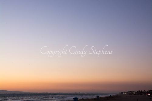 Pink and purple hues with colored lights along the California coastline