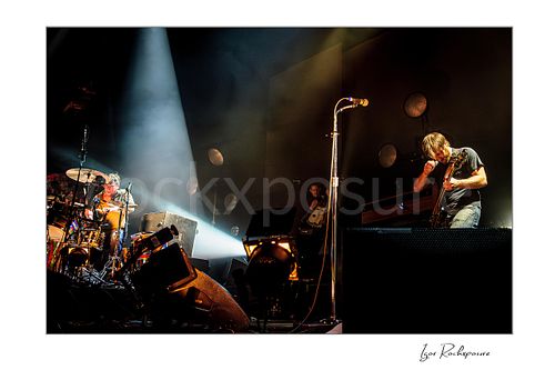 Horizontal color image of Dan Auerbach and Patrick Carney of The Black Keys performing live on stage under a dramatic spotlight