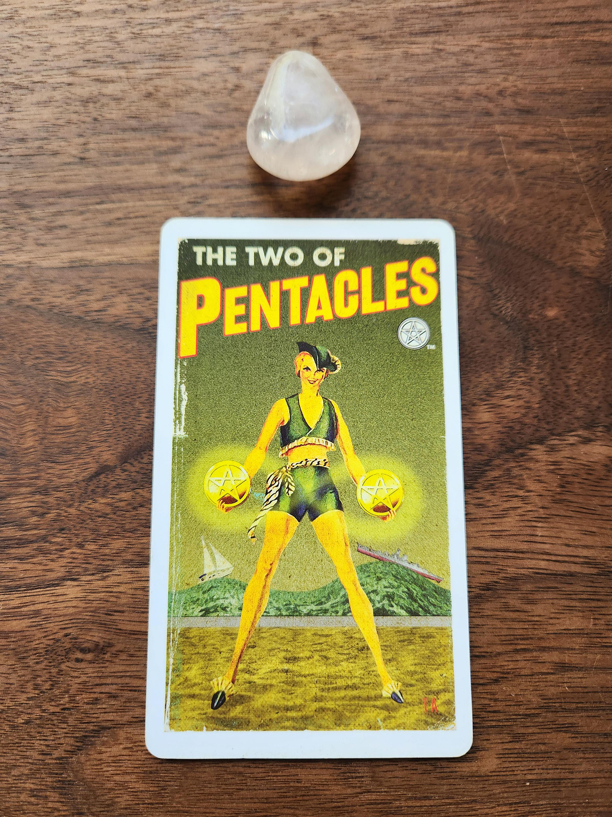 Two of Pentacles card and a rose quartz crystal.